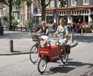 Two women ride their bicycles on the Lindengracht market in Amsterdam in August 2004. Credit: Michael Kooren/Reuters