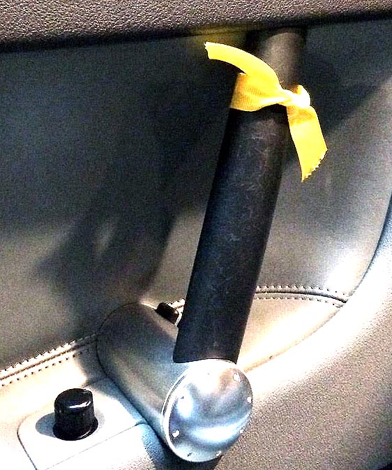 Ribbon tied to car door latch to remind driver or passenger to use Dutch Reach far hand habit to open car door and avoid injury of cyclist, getting oneself or door damage hit by traffic.