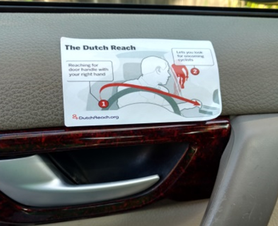 Boston Globe diagram on how to perform the Dutch Reach habit to avoid car doorings of cyclists by using far hand to reach across to unlock latch, forcing body to turn. This allows driver or passenger to swivel head to scan directly back to look for on-coming bicyclists or other traffic.