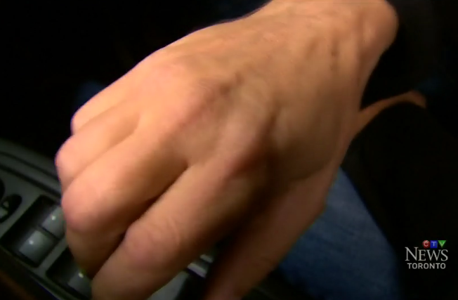 Image of a right hand on inside car door latch/ handle, doing the Dutch Reach anti dooring maneuver in a video produced by Canadian TV Toronto, October 13, 2016 explaining the Dutch Reach.