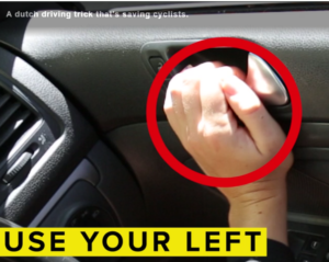 Woman's far hand on car door latch, to open car door using the far hand Dutch Reach method.
