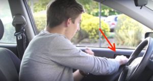 Photo: Young male driver seen reaching across with far hand (right for right side of road dirvers) to open car door latch, initiating Dutch Reach anti dooring maneuver.