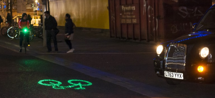 Projected outlines of bikcycle signage in green fluoescent color warns other road users of oncoming bicycle. Intended to increase night bicycling safety in London.