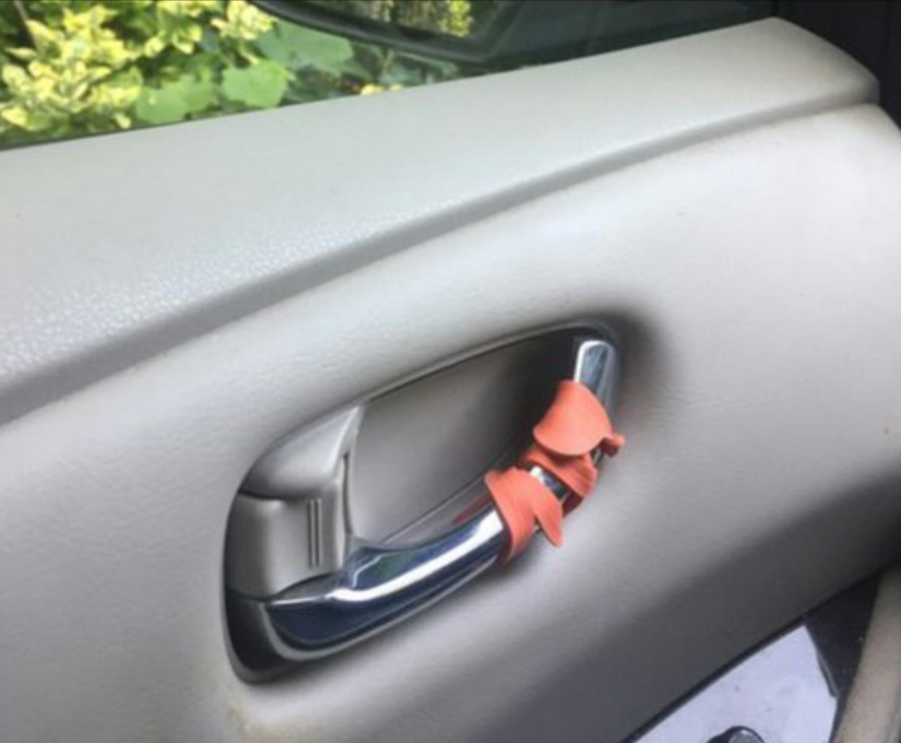 red rubberband wrapped on driver's car door handle